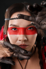 Shaman woman with face painting on black background