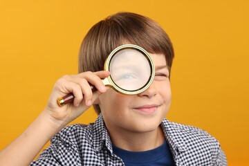 Little boy with magnifying glass on yellow background