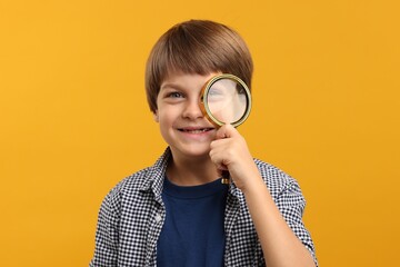 Little boy with magnifying glass on yellow background