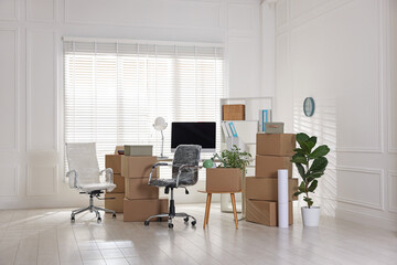 Moving day. Cardboard boxes, computer and furniture in office