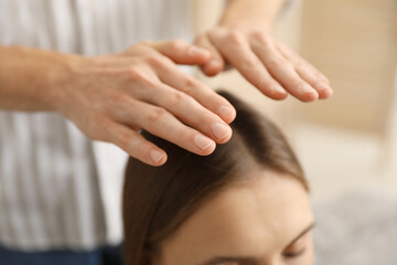 Reiki master healing patient's aura during therapy indoors, closeup