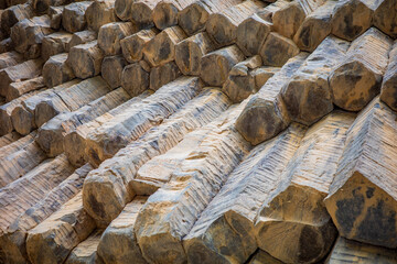 Close-up of hexagonal basalt columns formed by the cooling and fracturing of volcanic lava. The image captures the unique geometric pattern, earthy tones, and natural textures of the rock surface