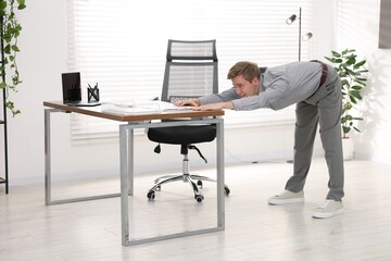 Young businessman doing stretching exercise in office