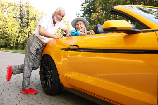 Stylish senior couple near modern cabriolet outdoors - Powered by Adobe
