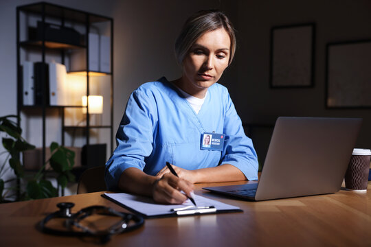 Medical assistant writing notes at table in clinic during night shift