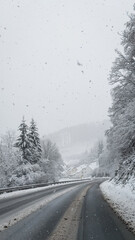 Snowy winter road through forest during snowfall