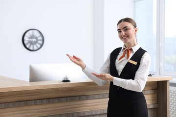 Happy receptionist in uniform welcoming near reception desk indoors