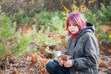 Teenager finding mushrooms in autumn forest outdoors