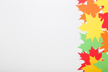 Created colorful different paper maple leaves from application paper on light gray table background. Closeup. Autumn decoration. Empty place for text. Top down view.
