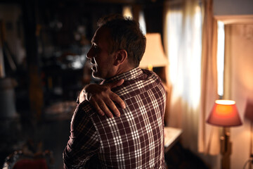 Man with shoulder, muscle, back and sciatica pain at home.