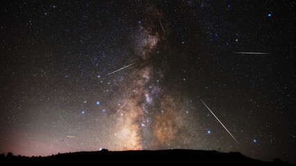 Fototapeta premium Milky way stars and constellations with landscape silhouettes photographed from a dark countryside location.