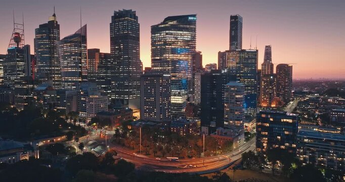 Australia, Sydney: Amazing Sydney's skyline cityscape at dusk, illuminated skyscrapers buildings, flowing night traffic, cars driving road, streets and iconic Sydney Tower. Aerial drone flight footage
