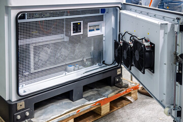 Inside view of a robust industrial electrical cabinet with its door open, revealing a metal mesh,...