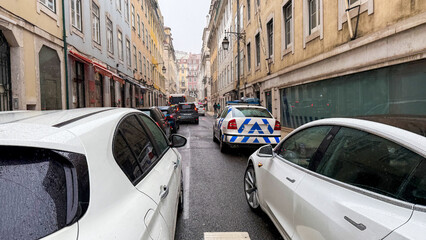Narrow urban street bustle, European architecture gleaming under foggy drizzle, reminiscent of...