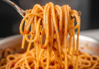 This close-up shot showcases perfectly cooked spaghetti coated in a rich, vibrant tomato sauce, ready to be enjoyed