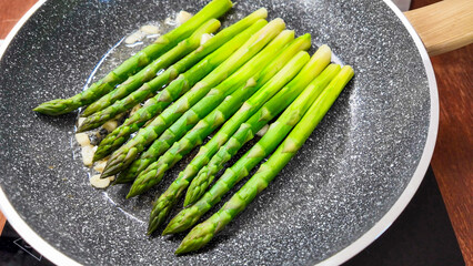Enticing green asparagus spears sizzle in a skillet, evoking spring rituals, Earth Day feasts, and gourmet alchemy