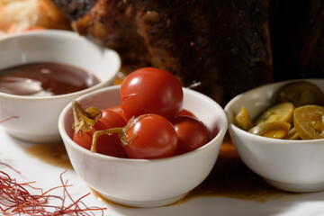 plates with marinated tomatoes, pickled green hot peppers and teriyaki sauce for a meat dish