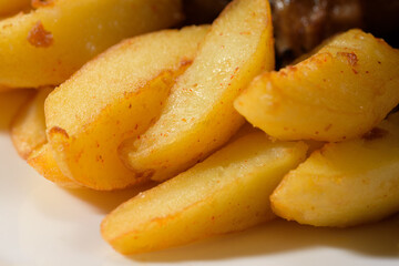 baked potato wedges close together, prepared to accompany meat
