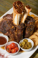 Beef shank on the bone with fermented cabbage, pickled tomatoes, baked potatoes, and teriyaki sauce