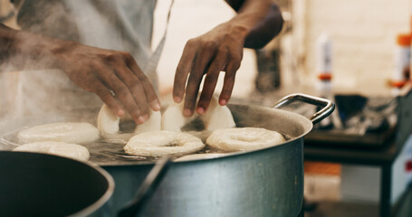 Chef, hands and bagels cooking in water for restaurant food, boiling starch and Polish cuisine....