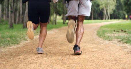 Fototapeta premium Fitness, legs and couple running outdoor for health, wellness or training with back. Man, woman and shoes of trail runner in woods for cardio workout, endurance exercise or practice in nature