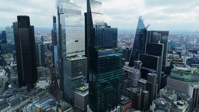 Aerial view of gleaming skyscrapers pierce the sky, their glass facades reflecting the diffused daylight, creating a mosaic of urban grandeur, London, United Kingdom.