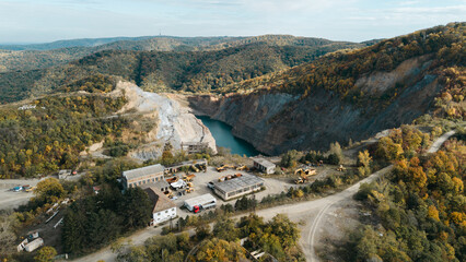 Aerial view of quarry and industrial buildings and cars near a turquoise lake in Fruska Gora,...