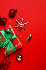 Vertical minimal red festive background with wrapped gift and decor, perfect for Christmas and New Year greeting design