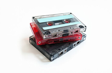 Obraz premium Three audio cassette tapes stacked together. Different colors red, black and transparent plastic shells on white background. Vintage analog media for music.
