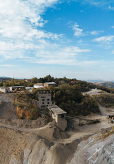 Fototapeta premium Aerial view of abandoned industrial buildings and quarry equipment in Fruska Gora, Serbia, surrounded by forested hills and dirt roads