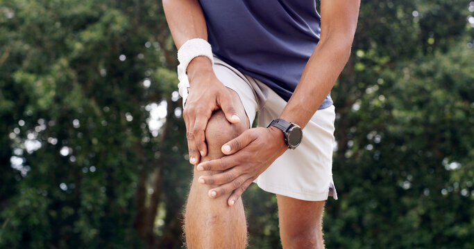 Fitness, hands and man with knee pain outdoor from sports injury, muscle fatigue and workout strain. PFPS, runner and kneecap dislocation in nature with joint inflammation, exercise sprain and bokeh