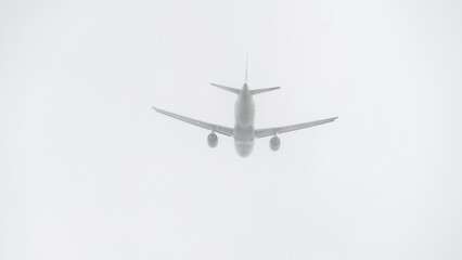 A white airplane is flying through a cloudy sky. The sky is overcast and the plane is the only object visible