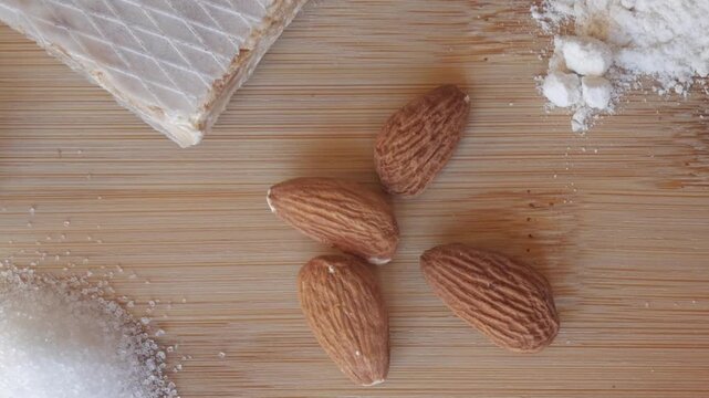Close-up of marzipan and almonds on a wooden board with sugar and honey under warm natural light, representing traditional Spanish sweets.