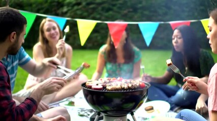 young friends enjoying a summer barbecue party together in a backyard garden.