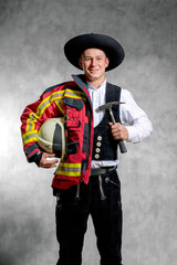 Symbolbild, Vereinbarkeit Beruf und Feuerwehrdienst. Zimmermann in Arbeitskleidung und Feuerwehr Schutzjacke.