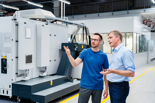 Employee talking to businessman in a factory
