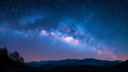 Fototapeta premium Starry night sky over silhouetted mountains and trees showcasing the Milky Way galaxy