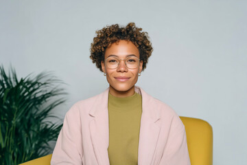 Portrait of confident young woman sitting on mustard yellow couch in cozy home interior
