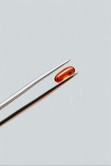 Translucent amber capsule held by tweezers on neutral background, macro pharmaceutical supplement and clinical research detail