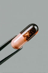 Close-up macro of translucent capsule held by tweezers on neutral background, innovative pharmaceutical supplement and biotech research concept