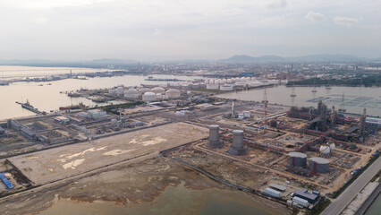 large oil tanker docked at a refinery terminal with multiple white storage tanks, complex pipeline networks, and offshore loading platforms. Represents global oil logistics
