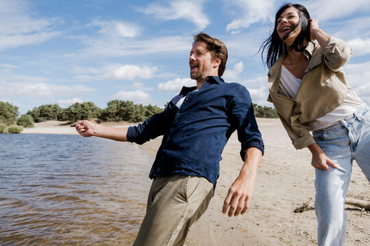 Couple having fun skimming stones on a windy beach outdoors