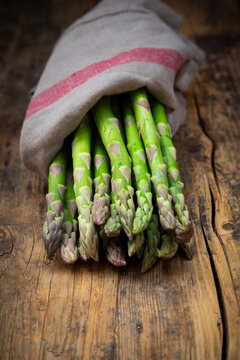 Green asparagus wrapped in kitchen towel on rustic wooden table