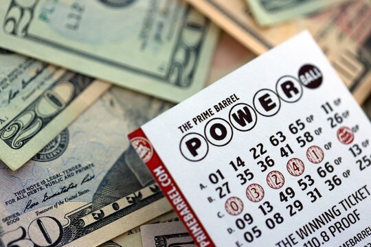 KYIV, UKRAINE - OCTOBER 22, 2025 Power Ball lottery ticket lies on many dollar bills close up