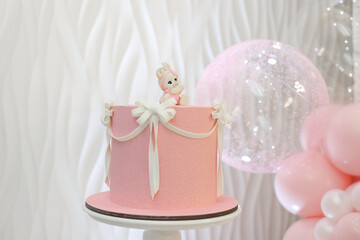 Luxury pink cake with white ribbons and bunny topper. Perfect dessert for baby shower, wedding, or birthday celebration. Elegant pastel decoration with soft pink balloons in background. High quality 