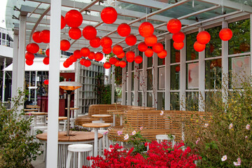 Cozy outdoor café terrace decorated with bright red lanterns hanging from a glass canopy in Sopot, Poland