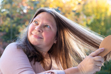woman combing long brown hair, tangles fallen hair wound on brush pins, hair loss, health,...
