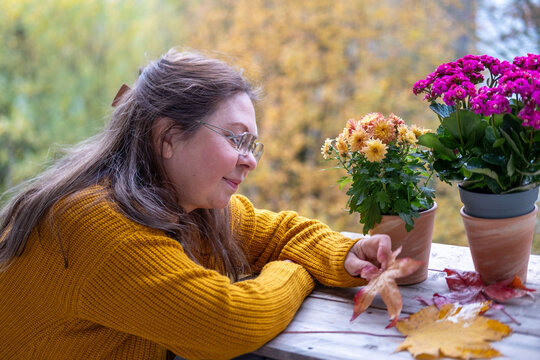 closeup female face, mature woman smiling outdoors in autumn wearing cozy clothes, flower aster season, serene moment with aster blooms, essence fall, possibly causing allergy - Powered by Adobe