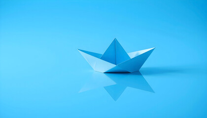 Origami boat sailing on reflective water &mdash; journey and ambition concept