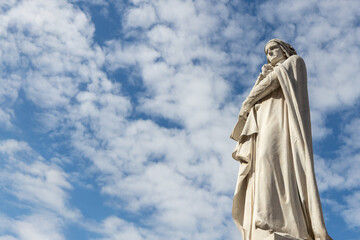 The Dante Alighieri statue in central Verona, standing against a cloudy blue sky, honoring the famous poet and reflecting the historic and cultural heritage of Italy